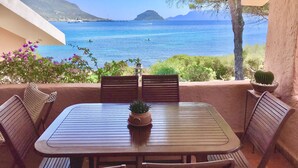 A patio with a table and chairs overlooking a coastal view. - VILLA BY THE SEA WITH GARDEN AND MAGNIFICENT TERRACE (Golfo Aranci)