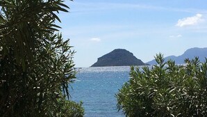 A stone pathway leading to a body of water with mountains in the background. - VILLA BY THE SEA WITH GARDEN AND MAGNIFICENT TERRACE (Golfo Aranci)