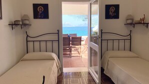 A bedroom with two beds, a view of the sea, and a balcony with outdoor seating. - VILLA BY THE SEA WITH GARDEN AND MAGNIFICENT TERRACE (Golfo Aranci)