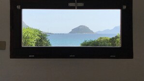 A television mounted on a wall with a view of a coastal landscape, including a body of water and distant mountains. - VILLA BY THE SEA WITH GARDEN AND MAGNIFICENT TERRACE (Golfo Aranci)