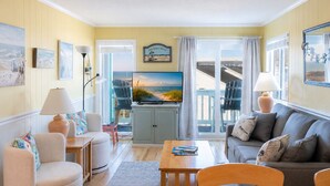 A living room with a television, seating, and a view of the ocean. - SeaSpray 350, Oceanview Condo in Atlantic Beach, NC! (Atlantic Beach)