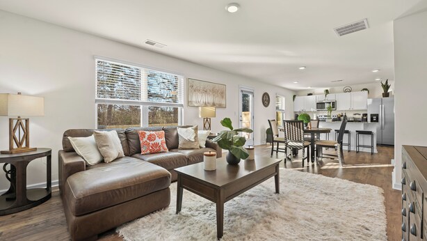 A modern living room with a brown leather sofa, a white shag rug, and a dining area with a wooden table and chairs. - Spacious 4-bedroom house in superb Rossville with WiFi and AC (Rossville)