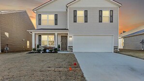 A two-story house with a front porch, garage, and a well-maintained lawn. - Spacious 4-bedroom house in superb Rossville with WiFi and AC (Rossville)