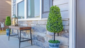 A stone house exterior with a wooden bench and two potted topiary trees. - Spacious 4-bedroom house in superb Rossville with WiFi and AC (Rossville)
