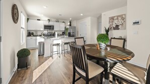 A modern kitchen with white cabinets, a central island, and a dining area with a round table and chairs. - Spacious 4-bedroom house in superb Rossville with WiFi and AC (Rossville)
