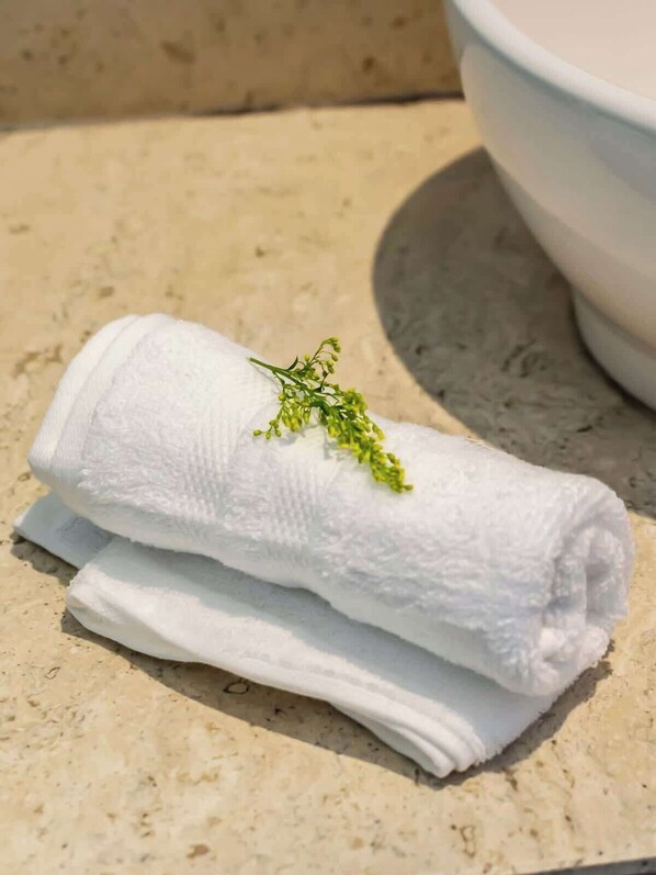 A white towel with a sprig of greenery on a stone surface.