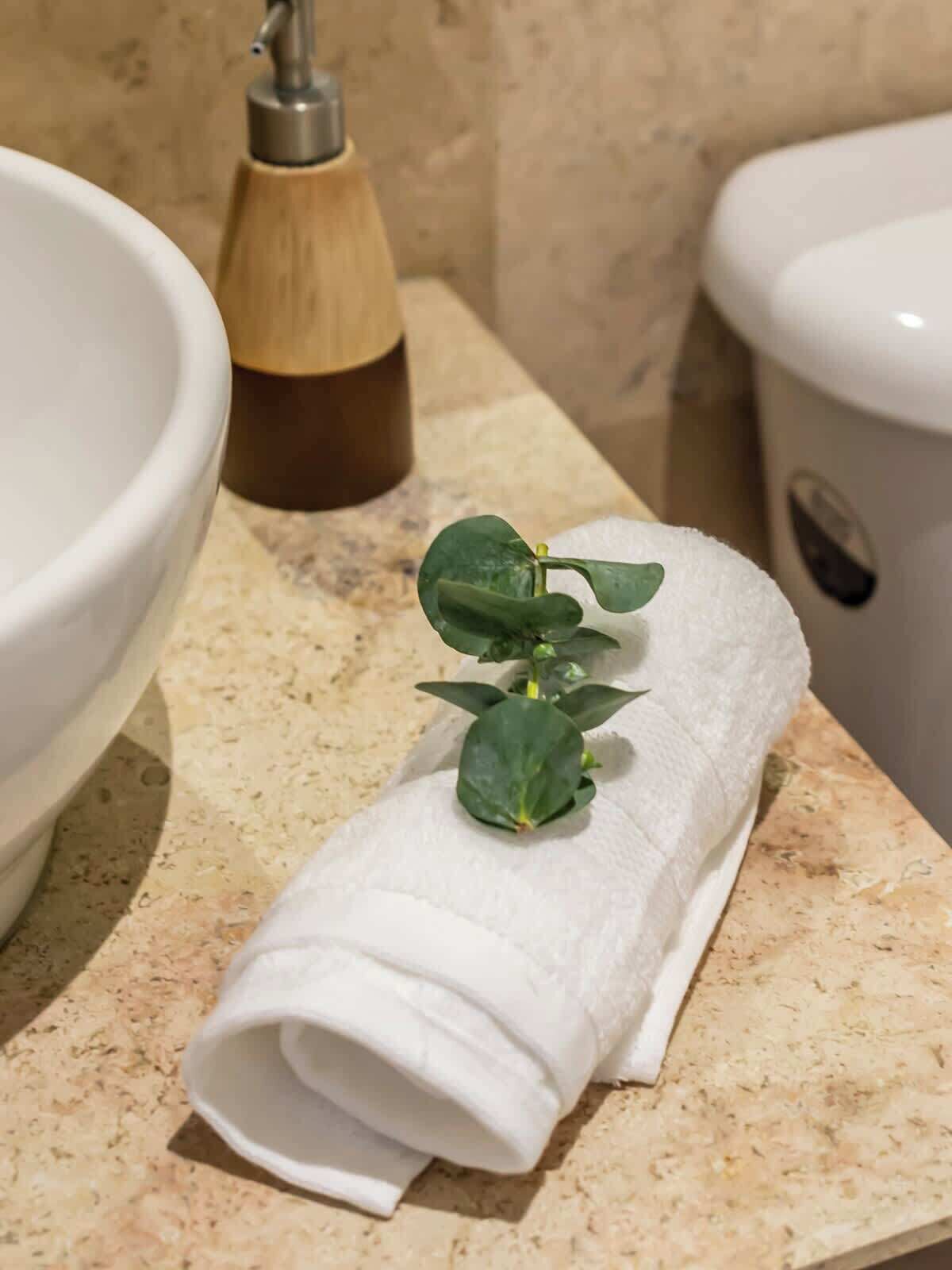 Une salle de bain avec un lavabo blanc, un distributeur de savon en bois et des toilettes.