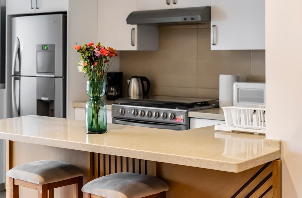 A modern kitchen with a central island, stainless steel appliances, and a vase with flowers.