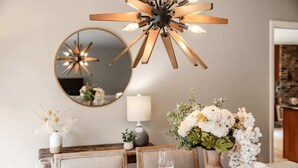 A dining area with a round table, chairs, a vase with flowers, a mirror, and a modern chandelier. - Serene 3b2b Home, Family-Friendly, Backyard & A/C (Redmond)