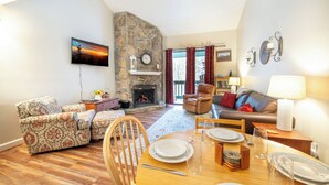 Una sala de estar acogedora con chimenea, un comedor preparado para cuatro personas y un espacio de descanso confortable.