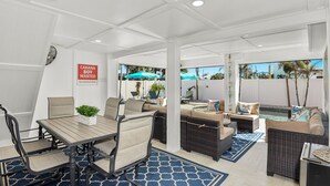 Un vaste patio intérieur comprenant un espace repas, des sièges et une vue sur la piscine.