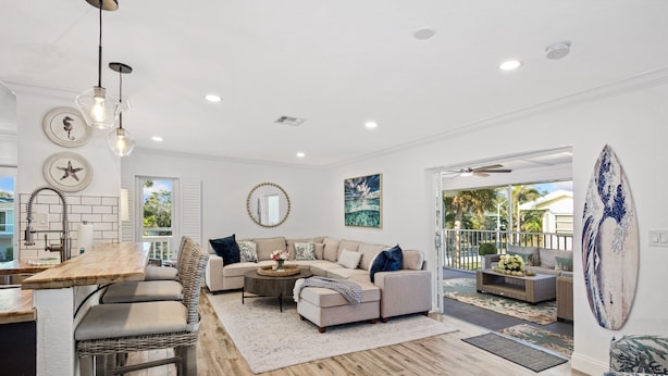 A spacious living area with a large L-shaped sofa, a dining table, and a bar area. - 🌊🏖️ Coral Cove B | Screened Porch + Pool | Steps to Beach + Times Square (Fort Myers Beach)