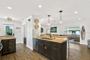 Una cucina moderna con mobili scuri, un piano di lavoro in legno e un'isola centrale con un lavello.