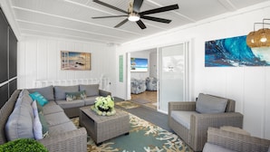 A spacious living area with a large sectional sofa, wicker furniture, and a ceiling fan. - 🌊🏖️ Coral Cove B | Screened Porch + Pool | Steps to Beach + Times Square (Fort Myers Beach)