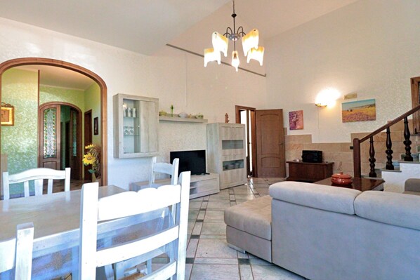 Amplia sala de estar con mesa de comedor, sofá y televisor.