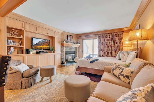 Una habitación acogedora con chimenea, televisión, sofá y cama.