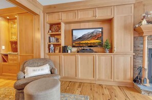 A living room with a television, wooden cabinets, a fireplace, and a cozy seating area.