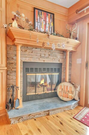 Una chimenea con detalles de piedra, una repisa decorada con una obra de arte enmarcada y un copo de nieve decorativo colgando en la parte superior.