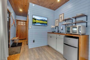 A kitchen with a refrigerator, microwave, and wooden cabinets.