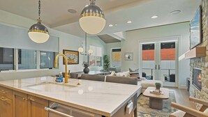 A modern kitchen with a large island, pendant lighting, and a stone fireplace. - Old Town Alpine Vista: Near Park City Ski Resort (Park City)