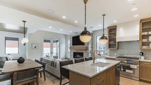 A modern kitchen with a central island, built-in oven, and a stone fireplace. - Old Town Alpine Vista: Near Park City Ski Resort (Park City)