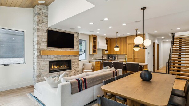 A modern living room with a stone fireplace, a flat-screen TV, and a dining area with a wooden table and chairs. - Old Town Alpine Vista: Near Park City Ski Resort (Park City)
