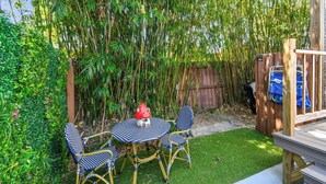 Eine Terrasse mit Tisch und Stühlen, umgeben von Bambuspflanzen und einem Holzzaun.
