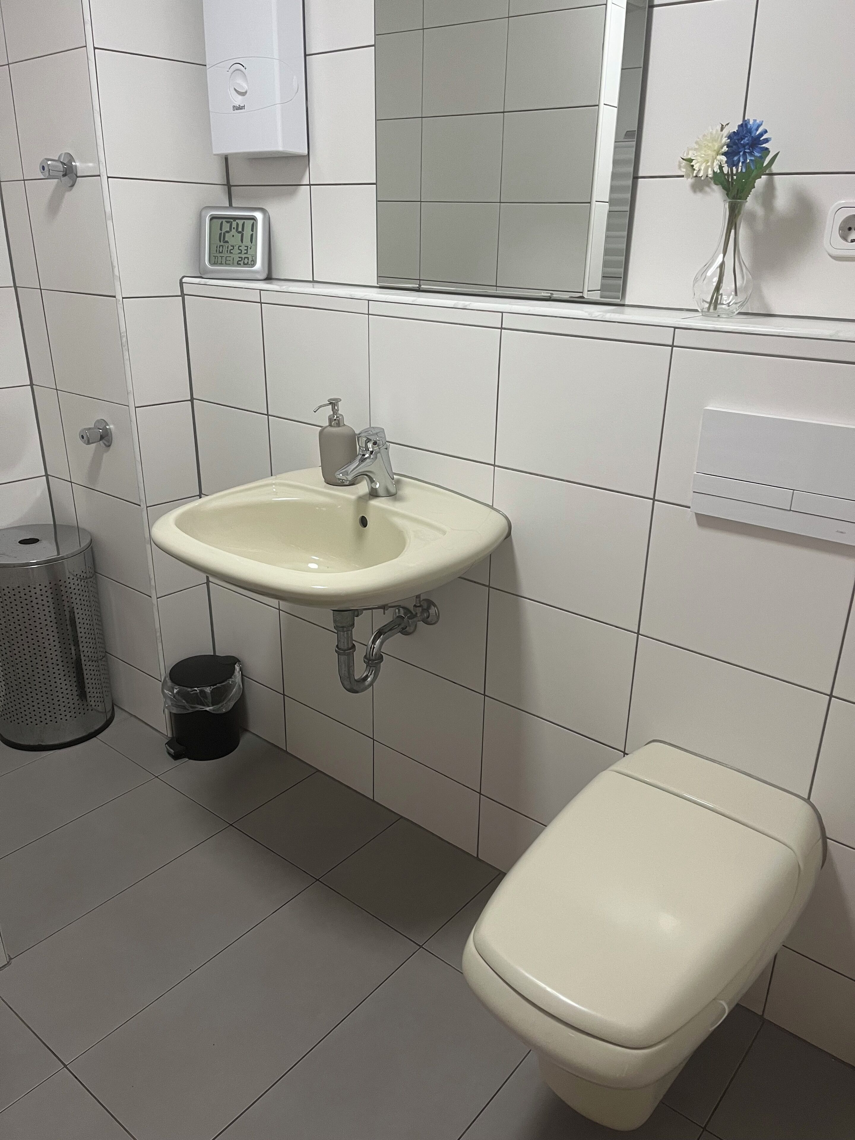 A bathroom with a toilet, sink, and a trash can.