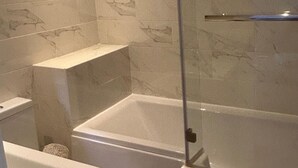Une salle de bain moderne avec une douche à parois de verre, une baignoire séparée et des toilettes.