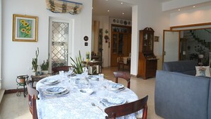 A dining area with a round table set for four, surrounded by chairs. A cabinet with glass doors is visible in the background. - Villa historic center sea view (Anzio)
