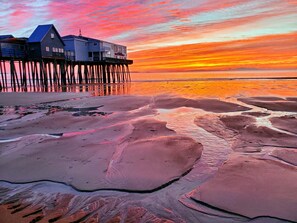 Ein Haus am Meer auf Stelzen mit Blick auf den Sonnenuntergang über dem Wasser.