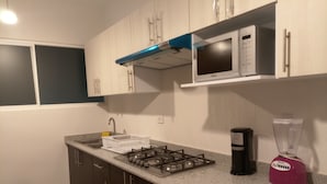 A kitchen with a gas stove, microwave, blender, and a sink with a dish rack. - Beach, your apartment near the sea and the Mayan Train (Playa del Carmen)