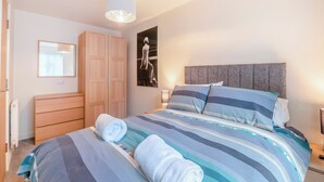 Quarto com cama, guarda-roupa, espelho e um quadro na parede.