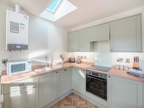 A modern kitchen with a skylight, built-in appliances, and light-colored cabinetry.