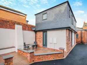 A two-story house with a patio, a satellite dish, and a door.