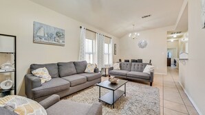 Un salon moderne avec deux canapés gris, une table basse et un tapis.