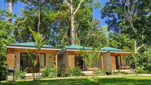 A row of modern, two-story cottages with green roofs, surrounded by lush greenery and trees. - Serenity Wave Bungalow (Cahuita)
