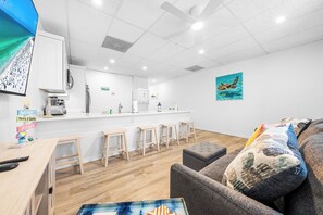 A modern kitchen with white cabinets, a countertop, and a bar area with stools. - Perfect Cozy Island Get-Away on Siesta Key! (Siesta Key)