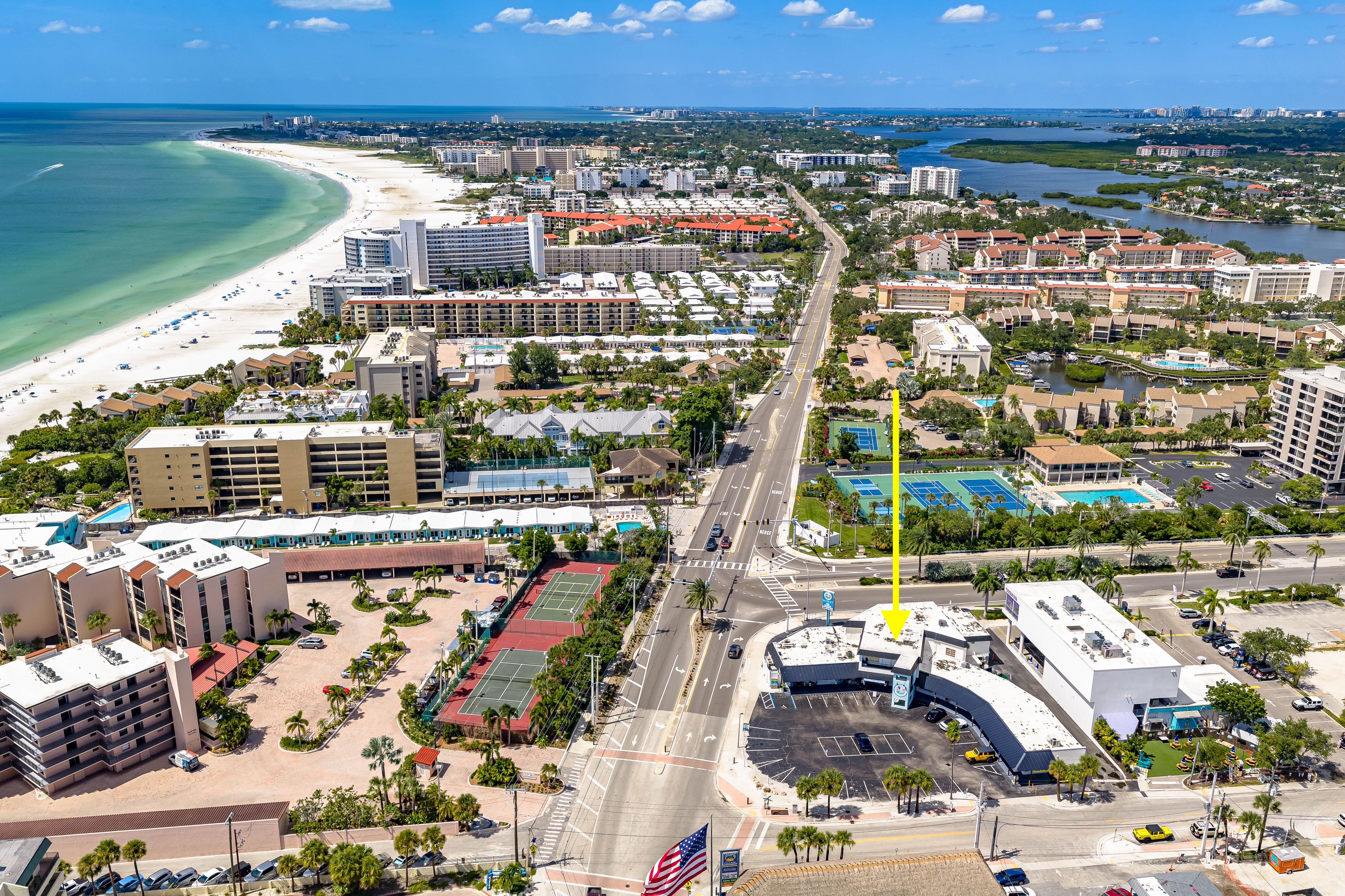 A coastal cityscape with a beach, hotels, and a marina.