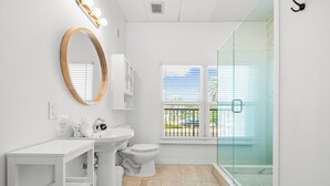 A bathroom with a toilet, sink, and a glass-enclosed shower. - Perfect Cozy Island Get-Away on Siesta Key! (Siesta Key)