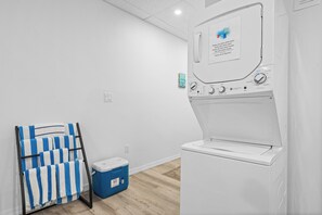 A laundry area with a white washing machine, a blue cooler, and a rack with striped towels. - Perfect Cozy Island Get-Away on Siesta Key! (Siesta Key)