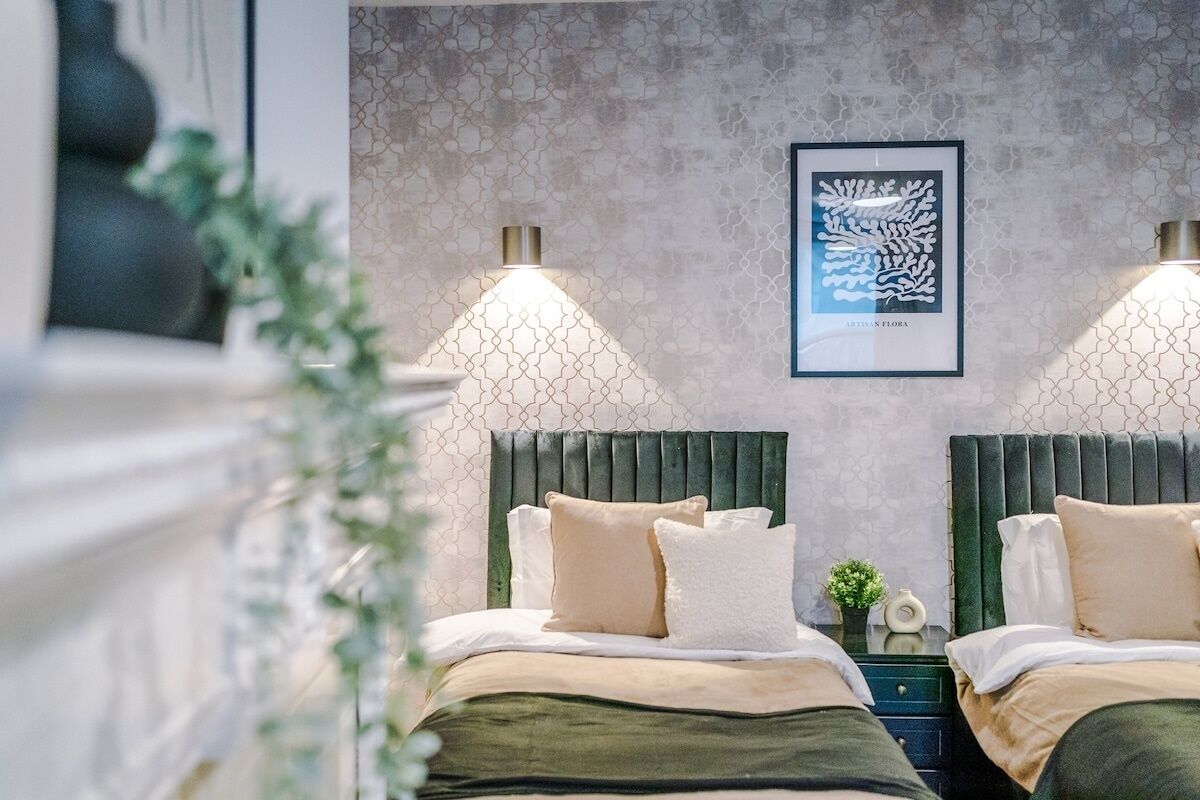 A modern bedroom with two beds, a textured wall, and a framed artwork.