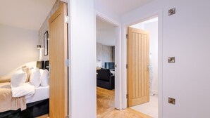A hotel room with a bed, a wooden door, and a hallway leading to another room. - Central York Penthouse With Private Roof Terrace (York)