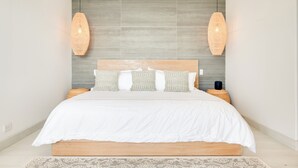 A modern bedroom with a large bed, two pendant lights, and a patterned headboard. - Romantic Getaway with Stunning Panoramic Ocean Views, Amazing Sunsets (Playa Flamingo)