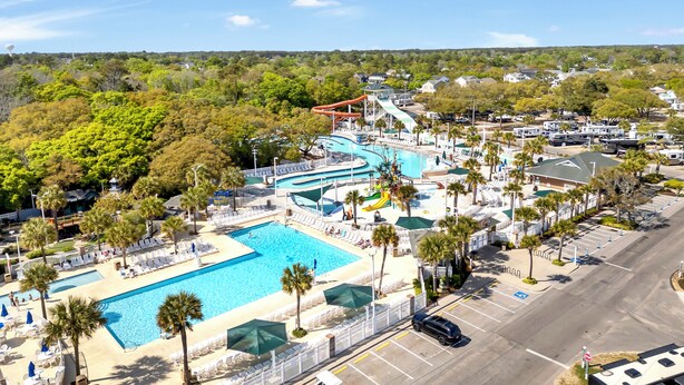 An aerial view of a resort with a large swimming pool, a water park, and a parking area. - Spacious 5-bedroom house with a quick walk or golf cart ride to the beach (Myrtle Beach)