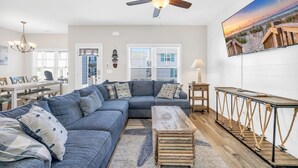 A modern living room with a sectional sofa, a wooden coffee table, and a ceiling fan. - Spacious 5-bedroom house with a quick walk or golf cart ride to the beach (Myrtle Beach)