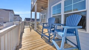 A wooden deck with outdoor seating and a covered area. - Spacious 5-bedroom house with a quick walk or golf cart ride to the beach (Myrtle Beach)