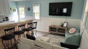 A modern kitchen with a bar area, a dining set, and a living room with a TV. - Center of Everything Southern Maine… 3-bedroom house, huge yard in Buxton (Buxton)