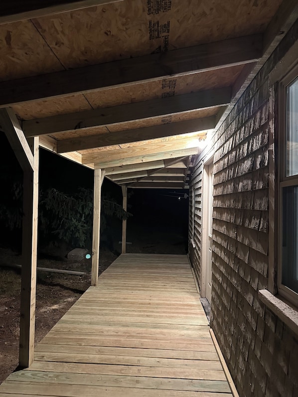 Une terrasse en bois couverte, d’où l’on peut admirer la façade d’un immeuble.