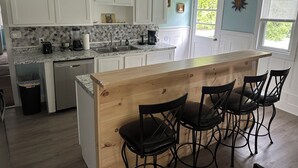 A kitchen with white cabinets, a granite countertop, a wooden island with bar stools, and a dishwasher. - Center of Everything Southern Maine… 3-bedroom house, huge yard in Buxton (Buxton)